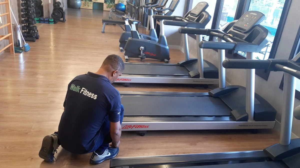 Técnico realizando manutenção preventiva em equipamento fitness